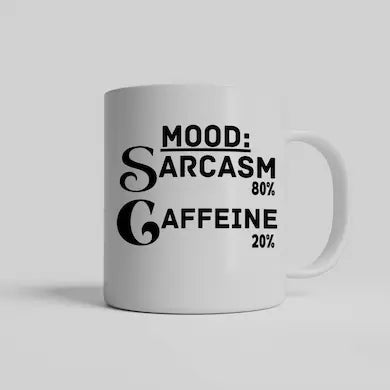 White ceramic coffee mug reading “Mood: Sarcasm 80% Caffeine 20%” in bold black lettering, sitting on a wooden desk beside a laptop and notebook.