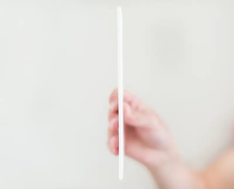 Hand holding a white straw against a light gray background