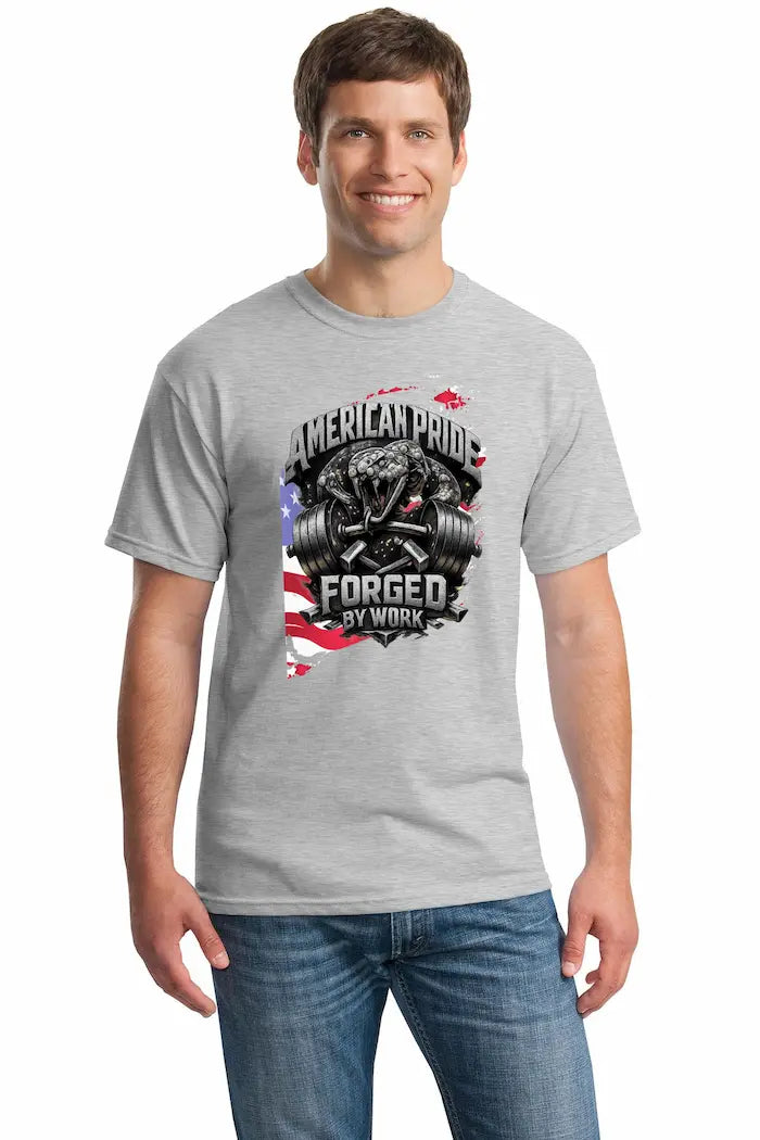 Cotton T-shirt with bold “American Pride – Forged by Work” text, modeled on a rugged workspace background.