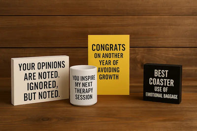 A selection of sarcastic and edgy gift items from the Comedy Corner collection displayed on a wooden table