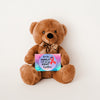 A plush teddy bear with a printed message card that reads 'We The Family Will Always Fight Together', indicating support for cancer research.