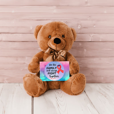 A plush teddy bear with a printed message card that reads 'We The Family Will Always Fight Together', indicating support for cancer research.