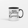 White ceramic coffee mug reading “Mood: Sarcasm 80% Caffeine 20%” in bold black lettering, sitting on a wooden desk beside a laptop and notebook.