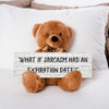 A teddy bear sitting on a wooden surface holding a sign with the phrase 'WHAT IF SARCASM HAD AN EXPIRATION DATE?'