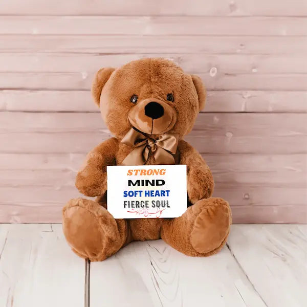 Brown teddy bear holding a sign with motivational text against a wooden background