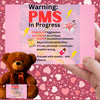 Bold comic-style PMS warning card with a pink storm background, cartoon icons like thunderclouds, chocolate bars, and explosive emojis, delivering a humorous and edgy message.