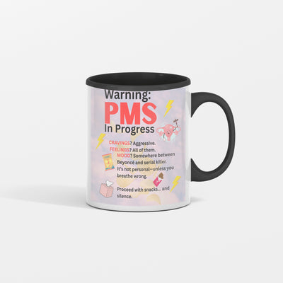 White ceramic coffee mug with bold text reading “PMS IN PROGRESS – Proceed at Your Own Risk” in a fun, comic-style font – perfect for women’s humor gifts.