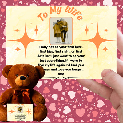 A soft plush teddy bear holding a heart-shaped tag and a printed card titled “To My Wife – Never Forget.” Set on a white gift box surrounded by roses and ribbon.