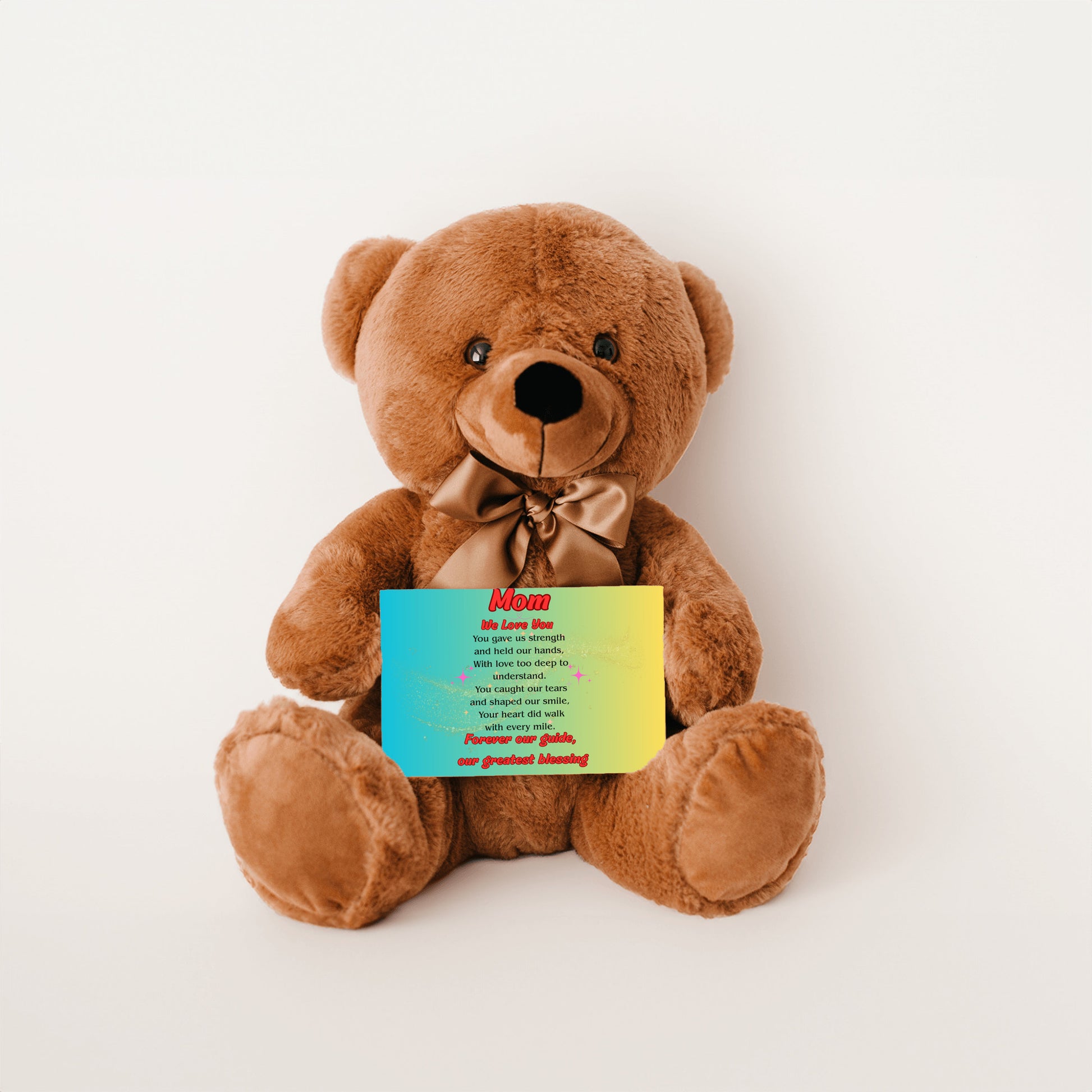"Plush teddy bear holding a card with the message 'Mom, We Love You – Forever Our Guide' on a pink floral background."
