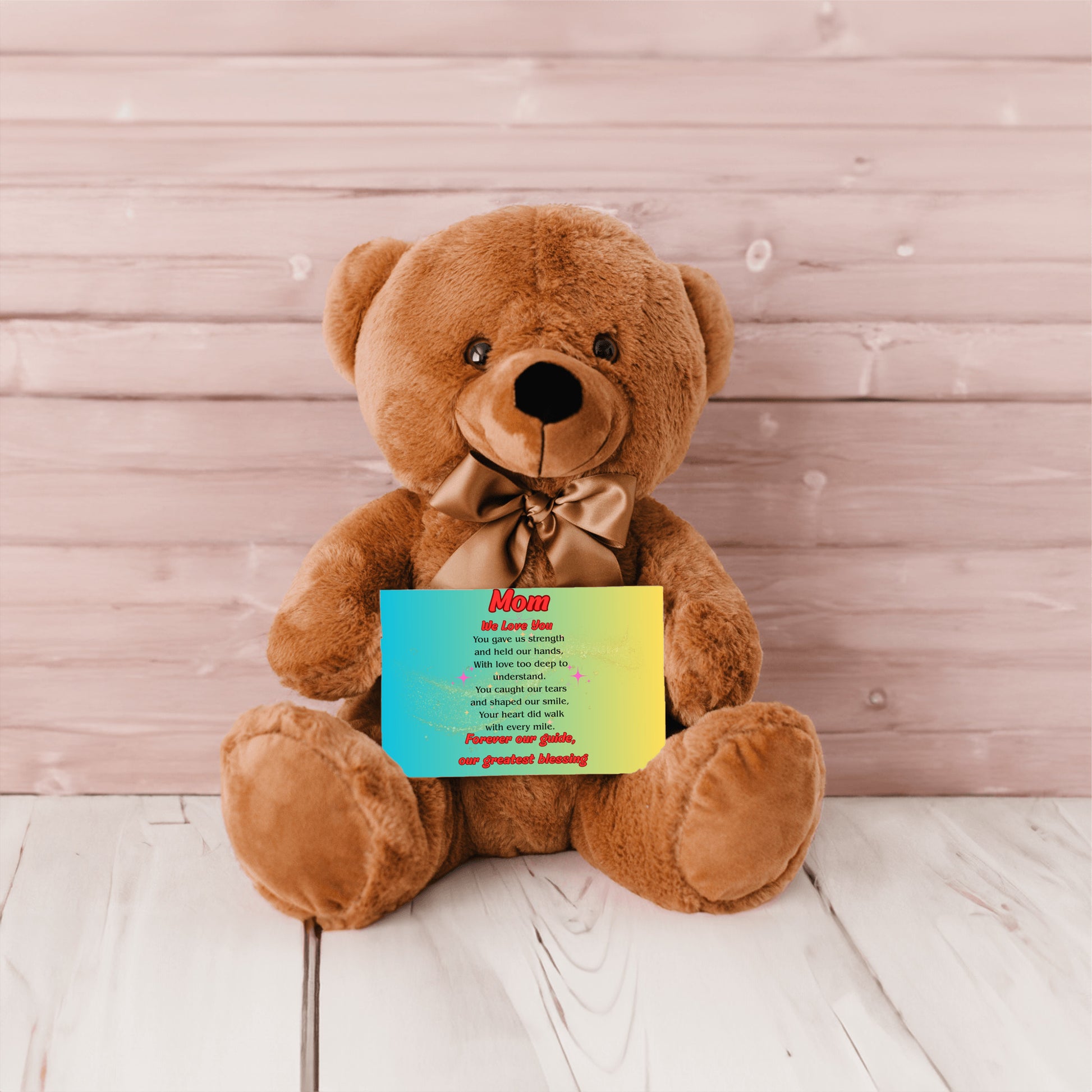 "Plush teddy bear holding a card with the message 'Mom, We Love You – Forever Our Guide' on a pink floral background."