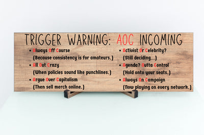 “All Out Comedy Plaque TRIGGER WARNING AOC Show political humor wall decor hanging on a wooden background”
