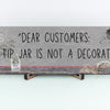 Funny bartender plaque that reads “Dear Customers: The Tip Jar Is Not Just a Decoration”