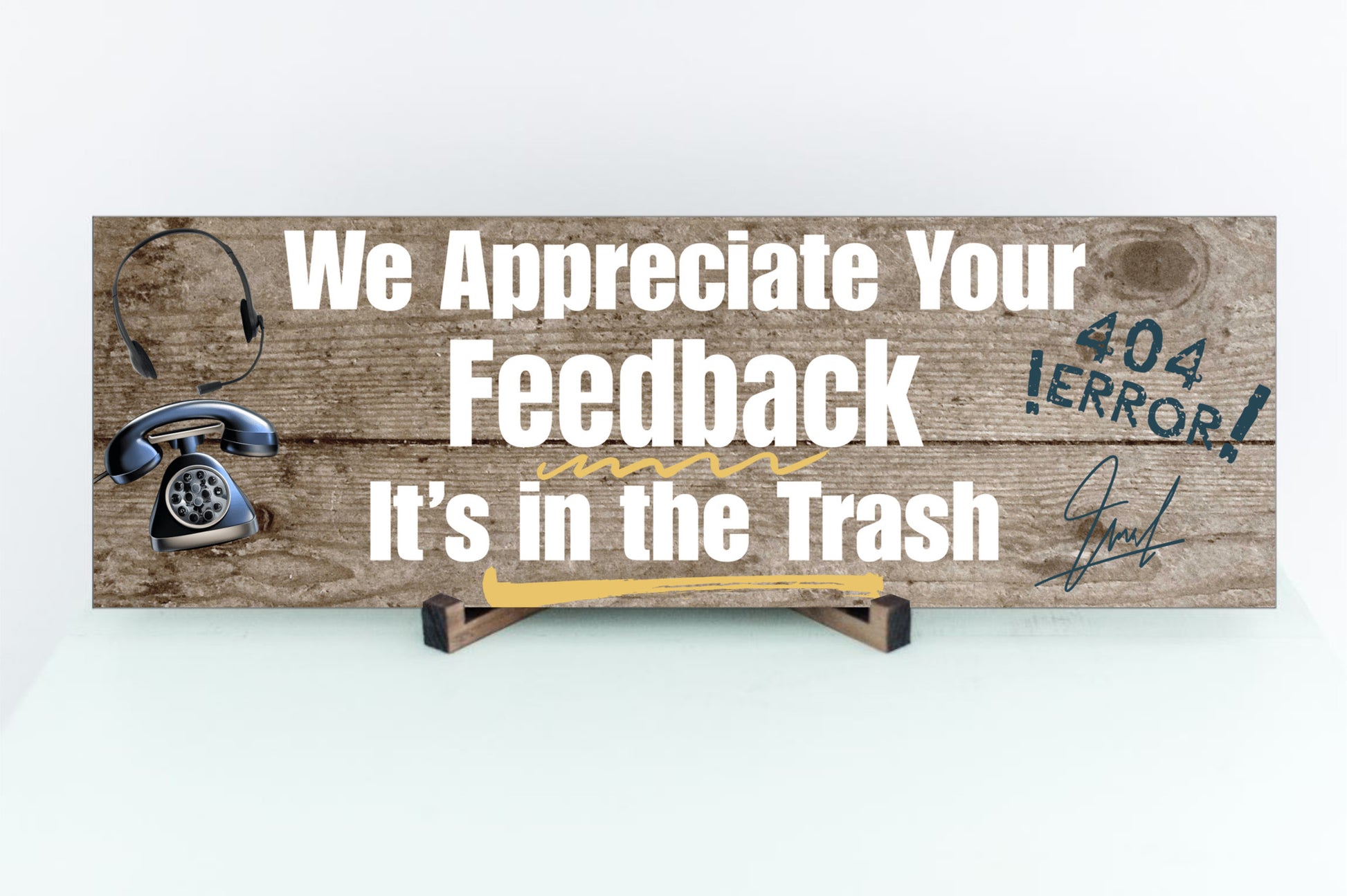 A rectangular wooden plaque featuring the sarcastic phrase "We Appreciate Your Feedback – It’s in the Trash" in bold white and red text on a dark vintage background with ornamental border details.