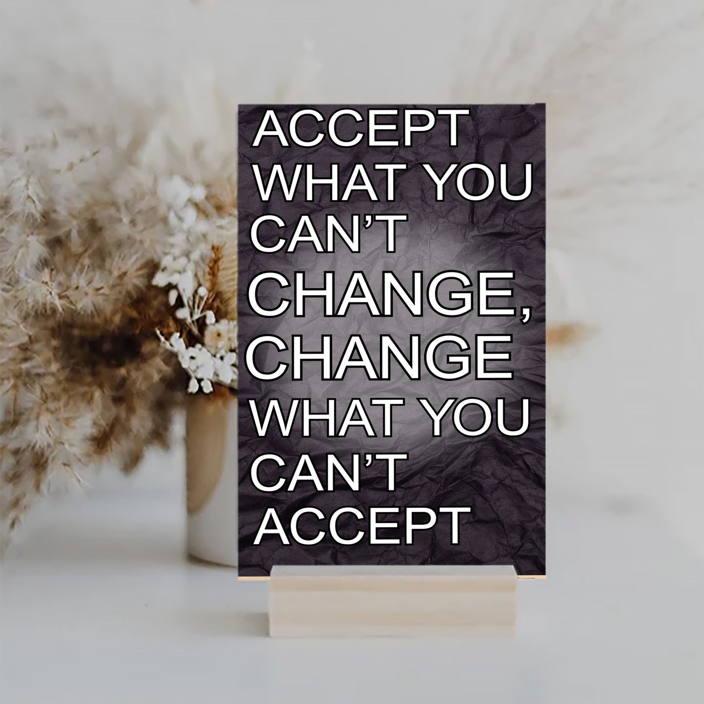 A wood-finish plaque with bold black text that reads “Accept What You Can’t Change” in capital letters, set in a clean and modern font.
