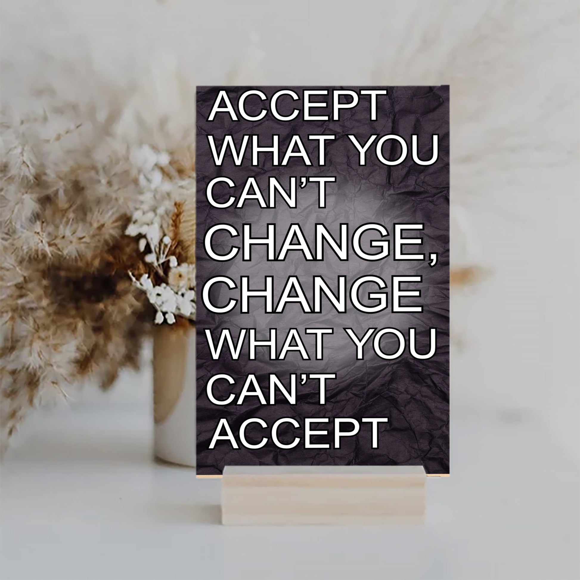A wood-finish plaque with bold black text that reads “Accept What You Can’t Change” in capital letters, set in a clean and modern font.