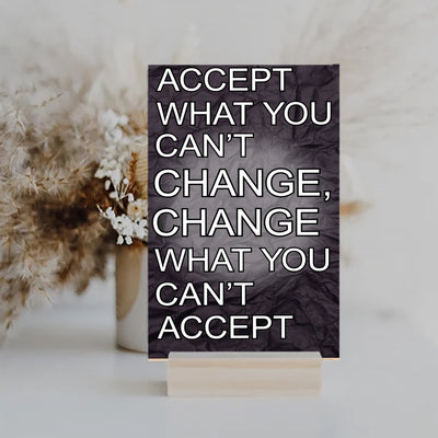 A wood-finish plaque with bold black text that reads “Accept What You Can’t Change” in capital letters, set in a clean and modern font.
