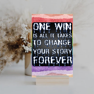 "Motivational wall plaque that reads ‘One Win Is All It Takes to Change Your Story Forever’ displayed above a desk workspace"