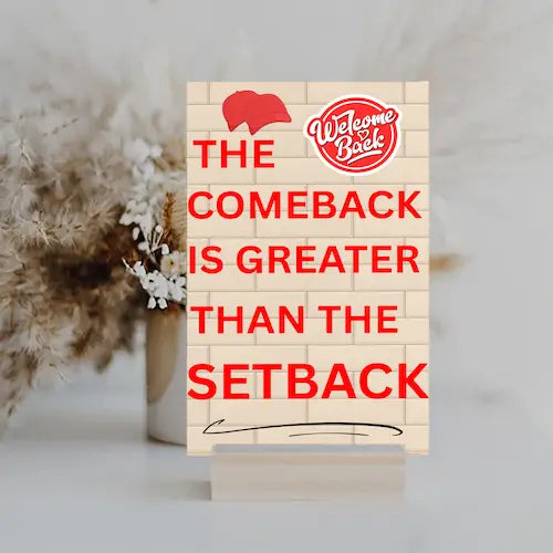 Motivational wall plaque with bold quote: “The Comeback Is Greater Than The Setback” in clean black-and-white print on wood, styled in a home office space.