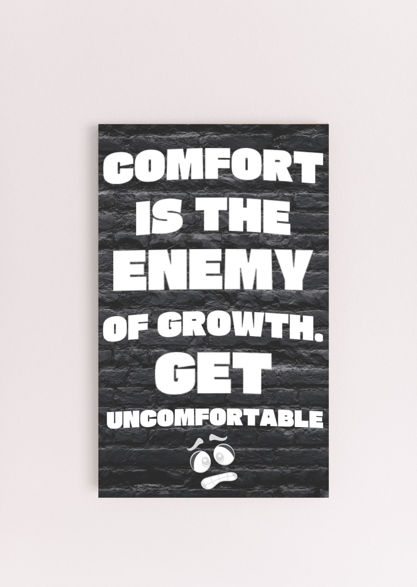 A modern wall plaque that reads “Comfort Is the Enemy of Growth” in bold, minimalist black letters on a clean woodgrain background.