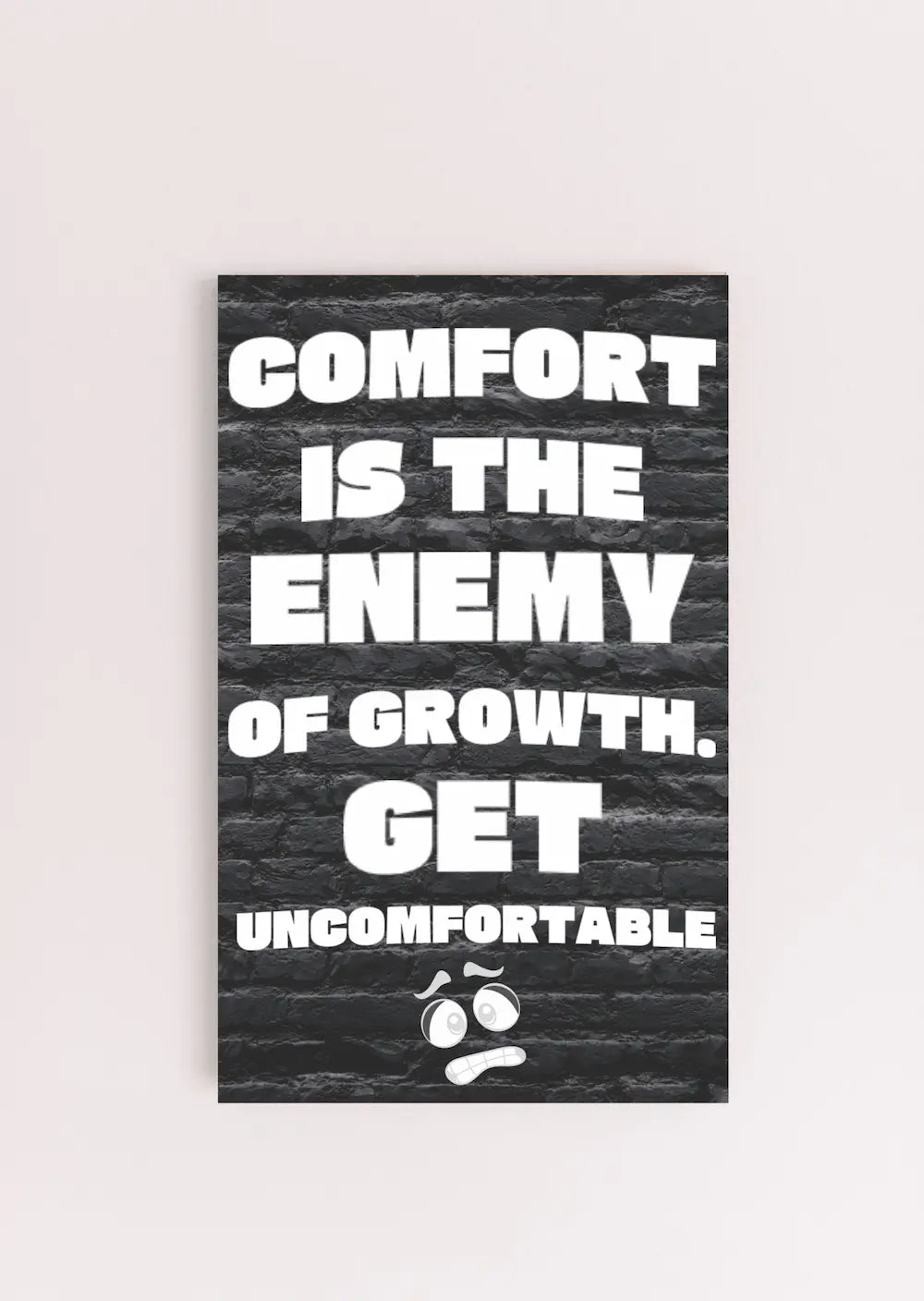 A modern wall plaque that reads “Comfort Is the Enemy of Growth” in bold, minimalist black letters on a clean woodgrain background.