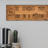 Wooden plaque reading “The Ultimate Mom” in bold script with floral accents and comic-style doodles, perfect for gifting or home décor.