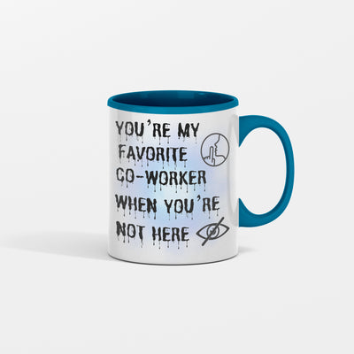 White ceramic mug with black text that reads, “You’re My Favorite Co-Worker (Please Don’t Read Into That).” Set against an office desk with pens and notepads.
