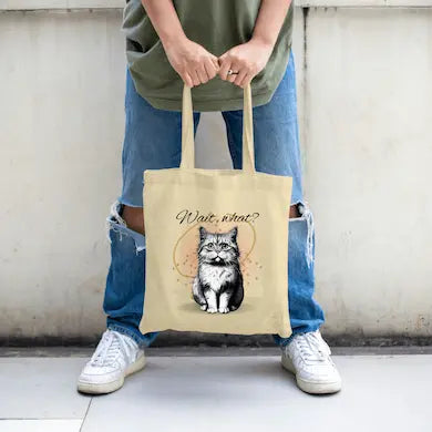 Funny canvas tote bag with shocked cartoon cat and large text “WAIT, WHAT?!” in expressive comic-style lettering.