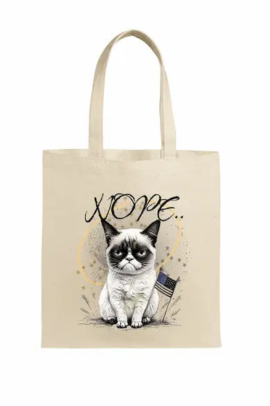 A beige canvas tote bag featuring a grumpy cartoon cat with the word “NOPE” in bold block letters.