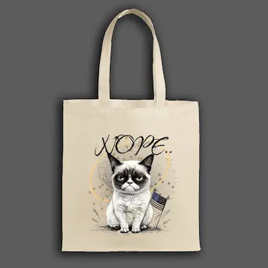 A beige canvas tote bag featuring a grumpy cartoon cat with the word “NOPE” in bold block letters.