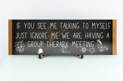 T-shirt with text: “If you see me talking to myself, just ignore me—we’re having a group therapy meeting.” Funny mental health quote tee in bold font.