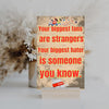 Wooden plaque with bold text: “Your biggest fans are strangers. Your biggest hater is someone you know,” styled with comic-style humor.