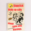 “Funny wall plaque reading 'Slapstick Wake Up Calls Should Come with Warnings' displayed on a kitchen wall near a coffee mug”