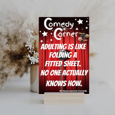 “Comedy wall plaque reading ‘Adulting is like folding a fitted sheet’ displayed in a cozy laundry room next to messy clothes”