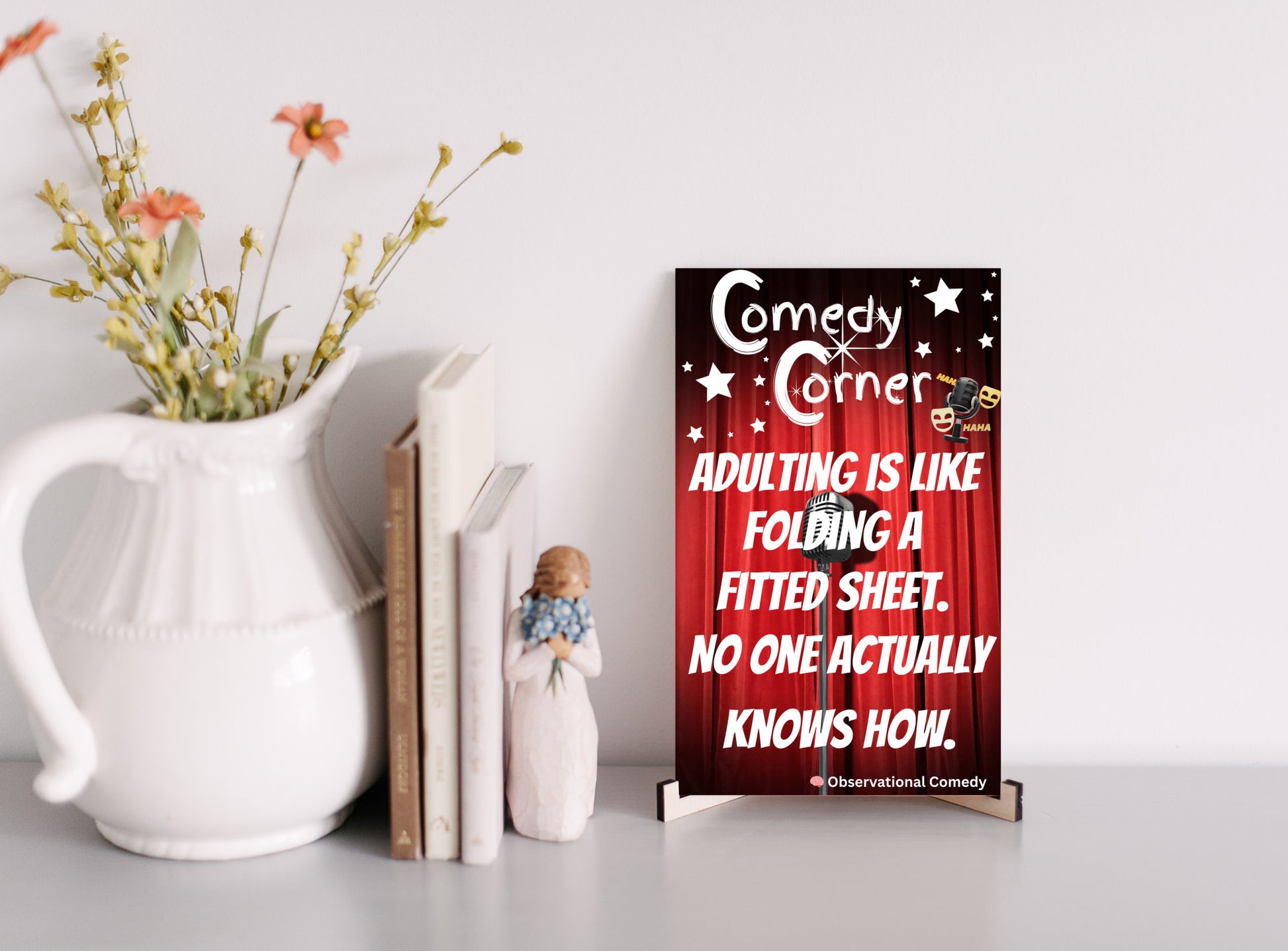 “Comedy wall plaque reading ‘Adulting is like folding a fitted sheet’ displayed in a cozy laundry room next to messy clothes”