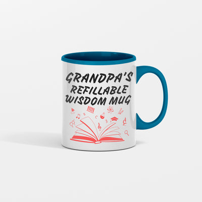 White ceramic coffee mug with bold black text that reads “Grandpa Refillable Wisdom Mug,” sitting on a rustic wooden table beside reading glasses.