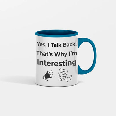 White ceramic coffee mug with bold black text reading “Yes I Talk Back. That’s Why I’m Interesting,” on a kitchen table with coffee steam rising.