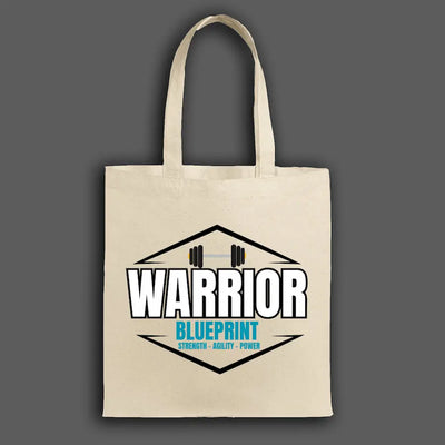 Cinematic shot of the Warrior Blueprint Tote Bag resting beside gym gear and a water bottle, morning light hitting the bold logo, symbolizing strength, motion, and warrior focus.