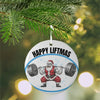 Christmas ornament with Santa Claus lifting weights and 'Happy Liftmas' text, hanging on a tree.