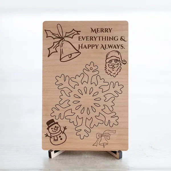 Laser-cut cherry wood postcard engraved with the phrase “Merry Everything & Happy Always,” displayed flat with festive accents.